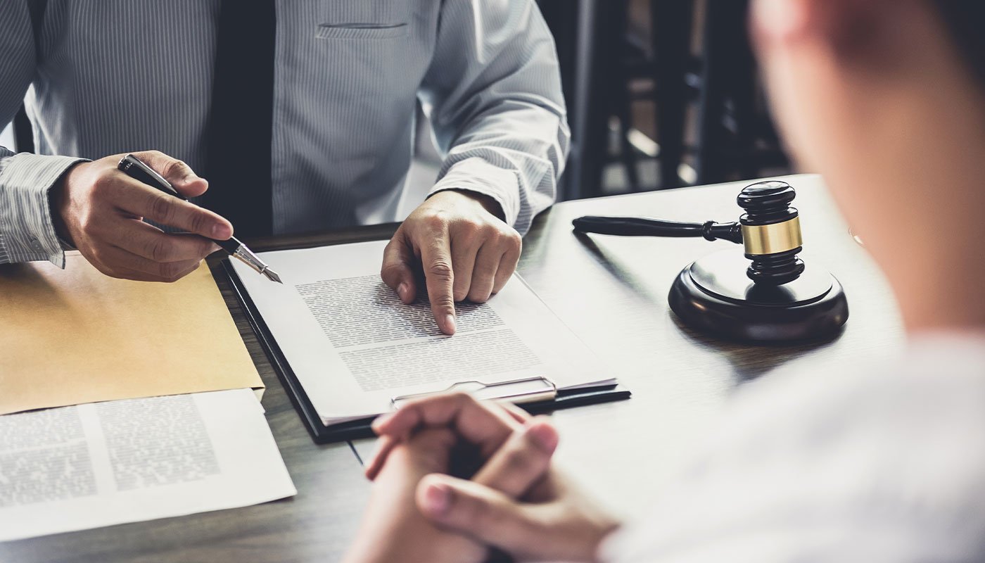 Closeup of a lawyer's desk and paperwork as he consults with a business person