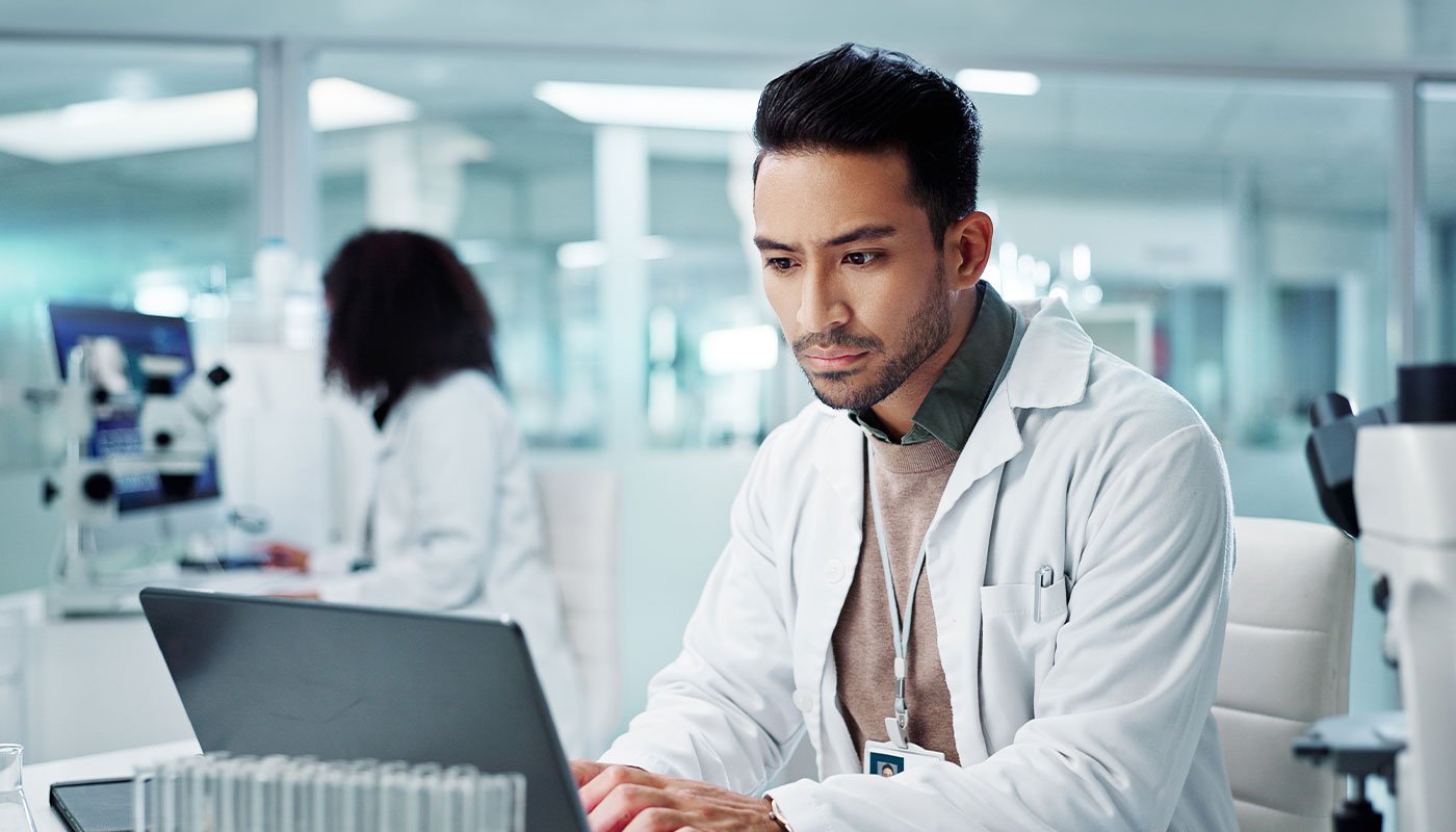 A doctor typing on a laptop in a lab