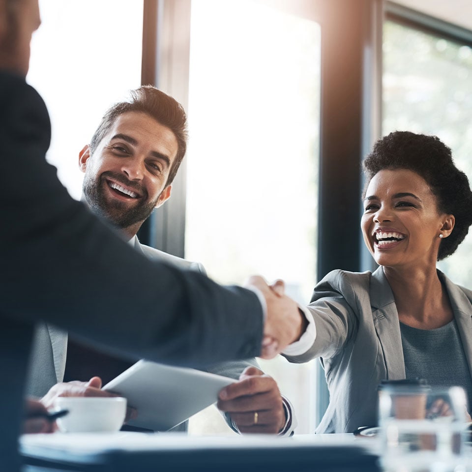 Shaking hands over table, person holding tablet