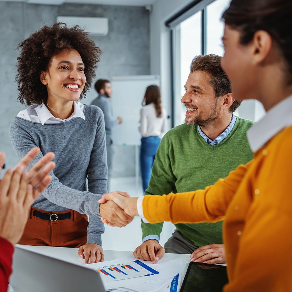 Group of business people having meeting in boardroom. Two female business partners shaking hands.