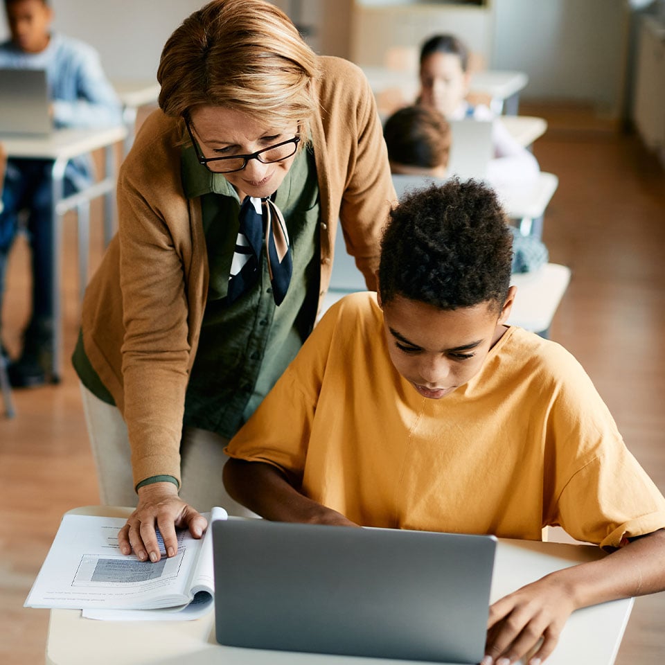 Teacher helping student on laptop 