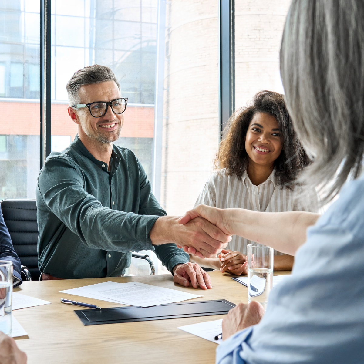 man shaking hands with women at conference table